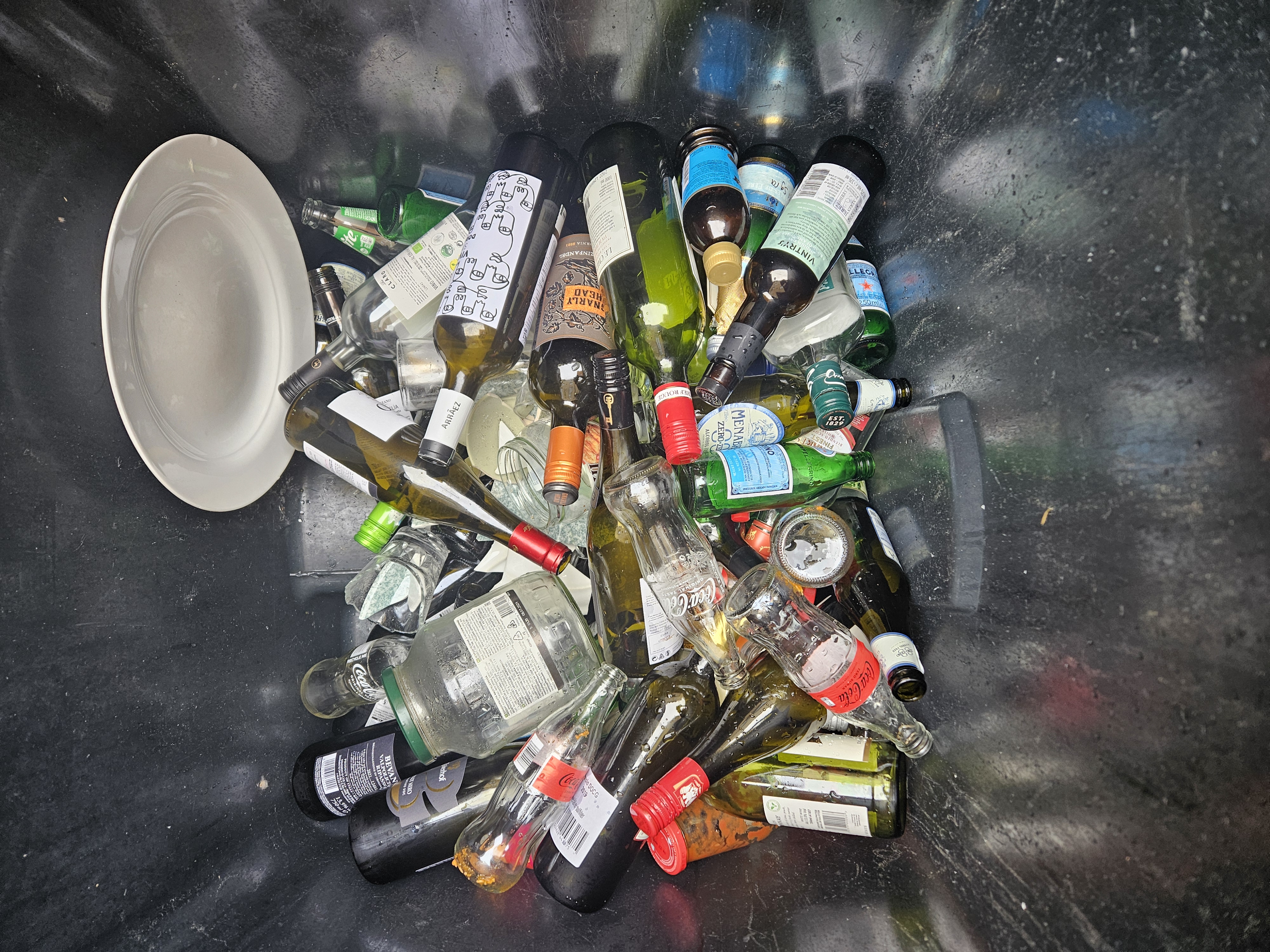 Cartons déchirés, bouteilles vides et déchets au sol derrière un restaurant