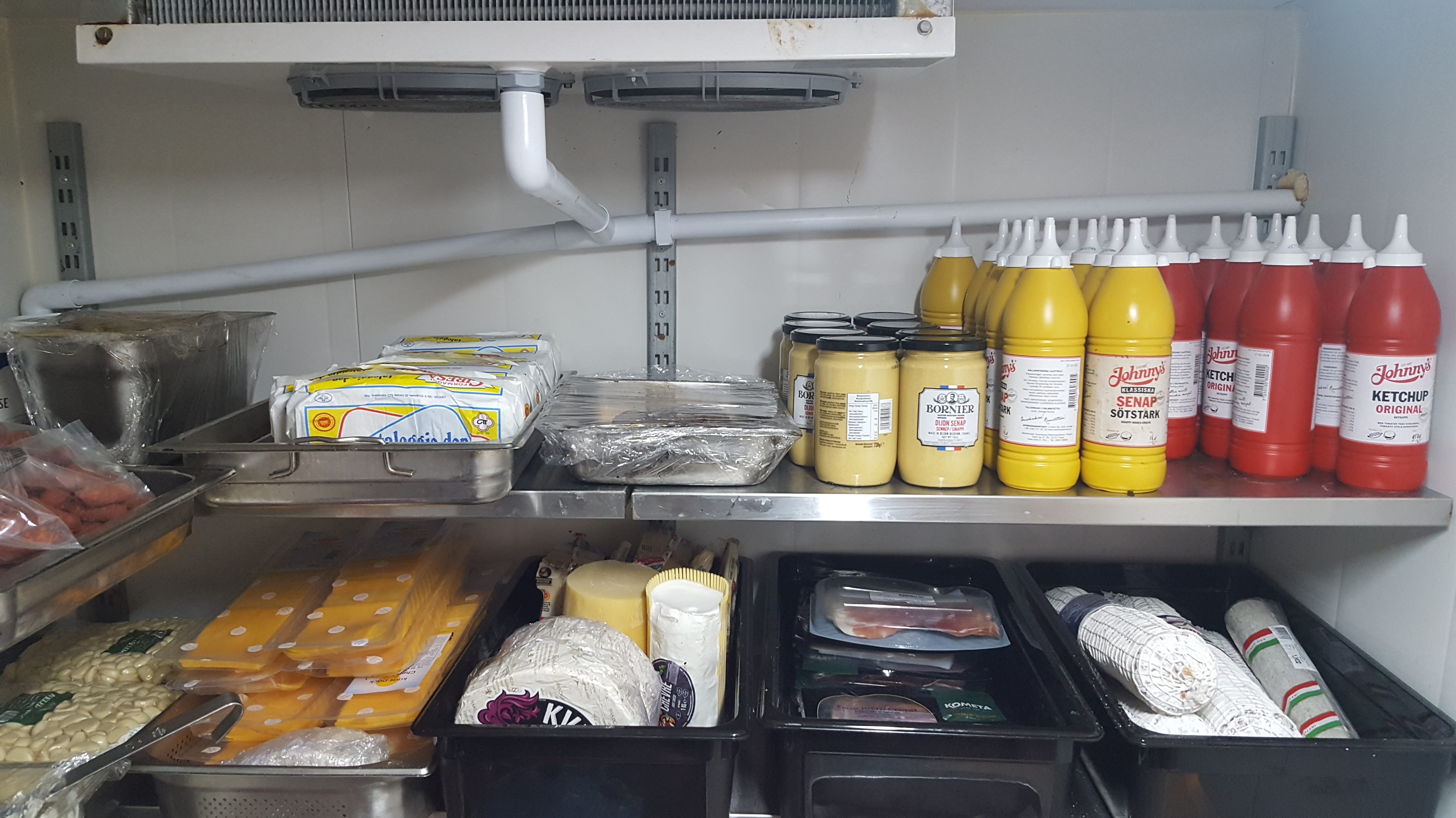 Cartons déchirés, bouteilles vides et déchets au sol derrière un restaurant